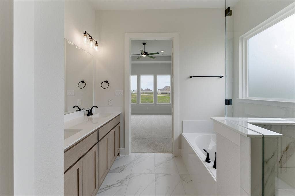 2204 Continent Court, Krum, TX 76249 Spacious bathroom featuring a double vanity with stone countertops, undermount sinks, and matte black fixtures