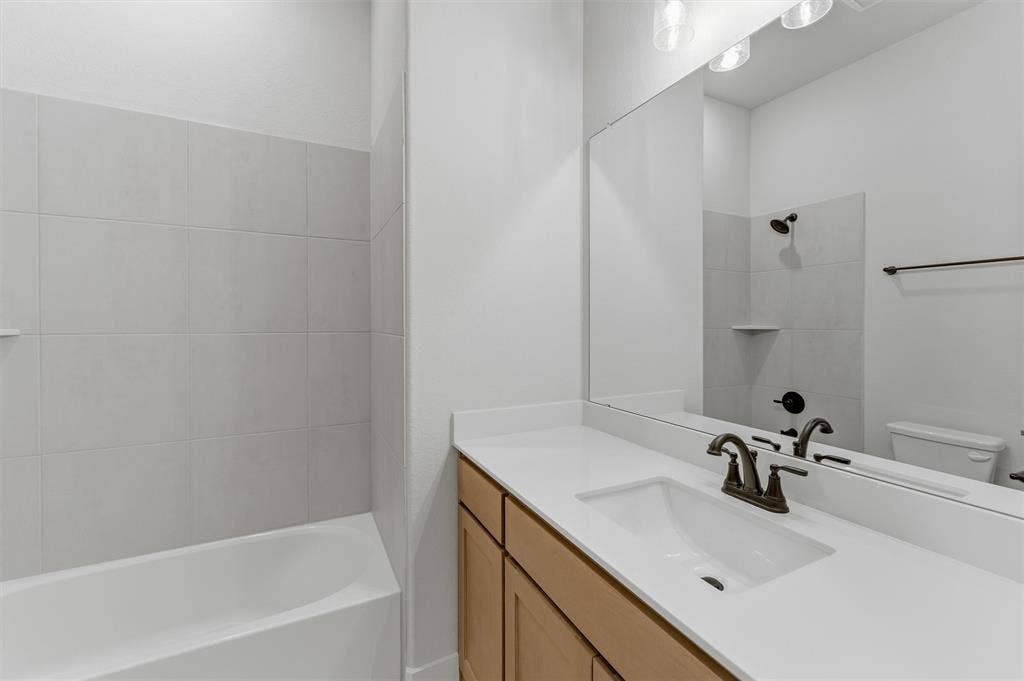 2204 Continent Court, Krum, TX 76249 Bathroom vanity featuring an integrated sink, broad countertop, and wood-finish cabinetry