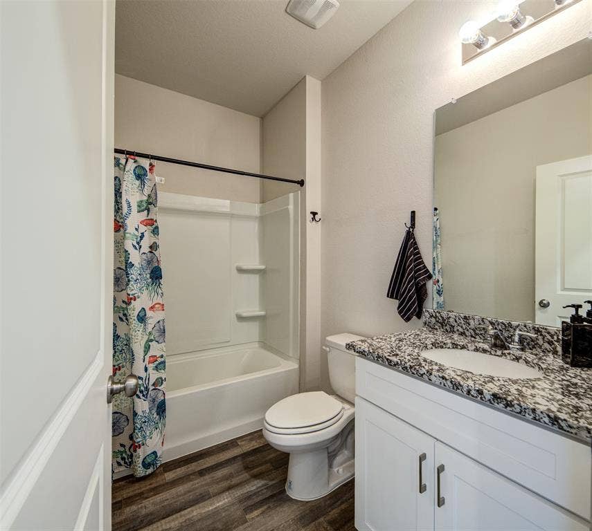 Full bath with vanity, shower / bath combo, and dark wood-type flooring
