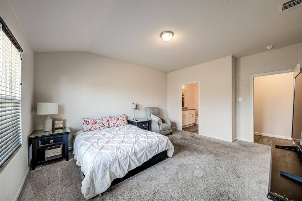 Bedroom featuring carpet floors, connected bathroom, and lofted ceiling
