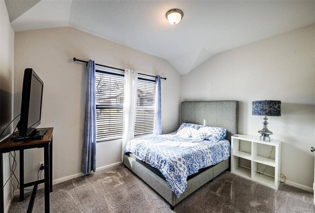 Carpeted bedroom featuring vaulted ceiling and baseboards