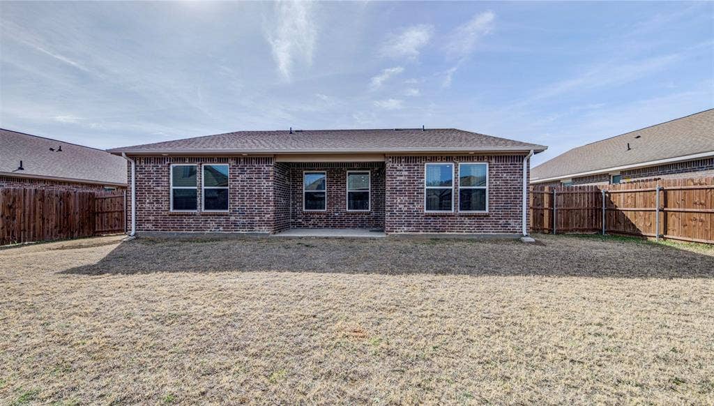 Back of property featuring a patio area, brick siding, a fenced backyard, and roof with shingles