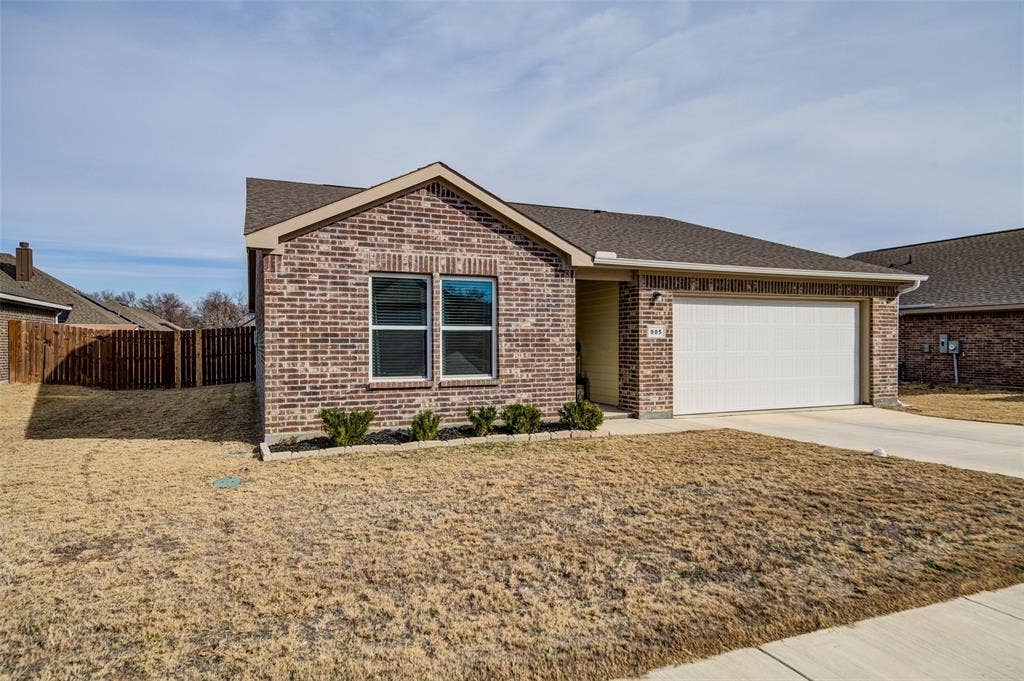 Ranch-style house with roof with shingles, driveway, brick siding, and a garage