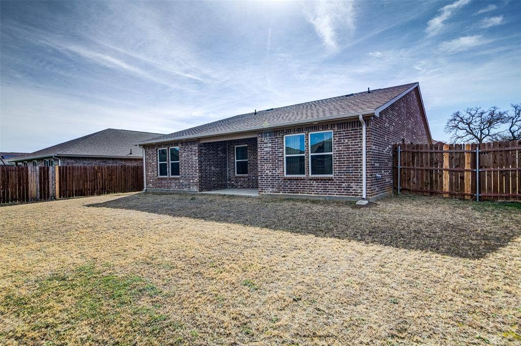 Back of property with a patio area, brick siding, a shingled roof, and a fenced backyard