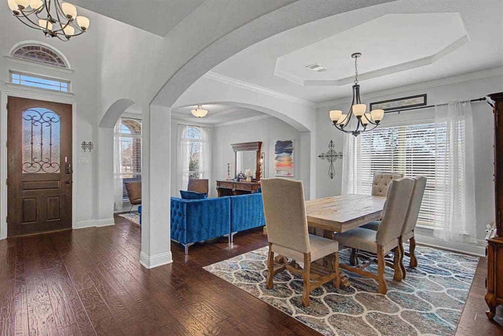 3409 Florence Drive, Corinth, TX 76210 Dining space with a chandelier, dark wood-type flooring, plenty of natural light, a tray ceiling, and crown molding