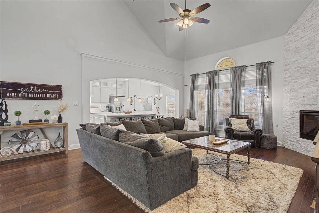 3409 Florence Drive, Corinth, TX 76210 Living room with a ceiling fan, dark wood-type flooring, a fireplace, vaulted ceiling, and arched walkways
