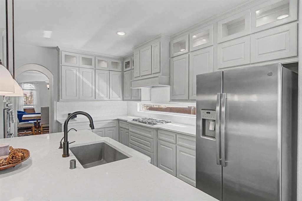 3409 Florence Drive, Corinth, TX 76210 Kitchen with stainless steel appliances, glass insert cabinets, light stone counters, arched walkways, and recessed lighting