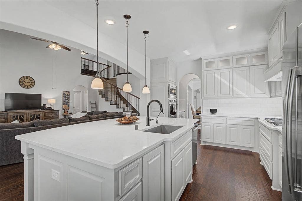 3409 Florence Drive, Corinth, TX 76210 Kitchen featuring arched walkways, hanging light fixtures, open floor plan, and a center island with sink