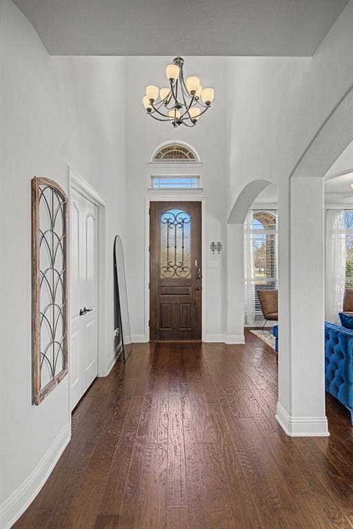 3409 Florence Drive, Corinth, TX 76210 Foyer featuring dark wood-type flooring, a chandelier, a high ceiling, arched walkways, and plenty of natural light
