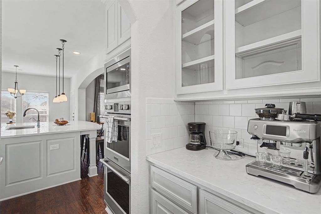 3409 Florence Drive, Corinth, TX 76210 Kitchen with white cabinetry, stainless steel appliances, light stone countertops, dark wood finished floors, and glass fronted cabinets