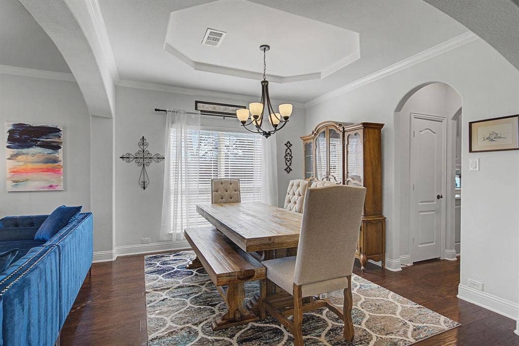 3409 Florence Drive, Corinth, TX 76210 Dining space featuring arched walkways, suspended lighting, dark wood-style floors, ornamental molding, and a tray ceiling