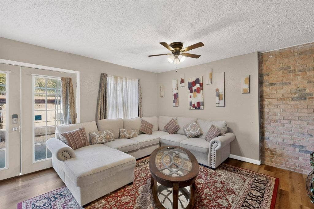 2315 Blue Sage Lane, Arlington, TX 76014 Living area with wood finished floors, ceiling fan, a textured ceiling, and brick wall