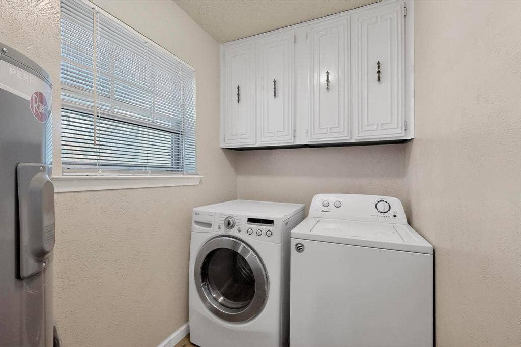 2315 Blue Sage Lane, Arlington, TX 76014 Laundry room featuring washer and dryer, a textured wall, water heater, a textured ceiling, and cabinet space