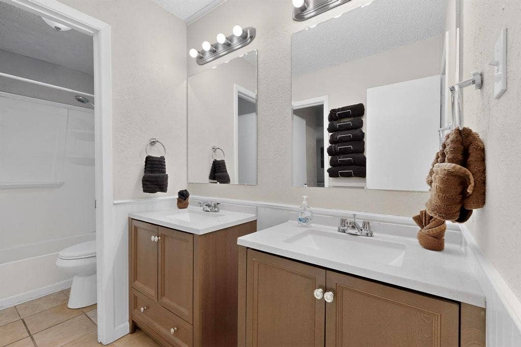 2315 Blue Sage Lane, Arlington, TX 76014 Bathroom with two vanities, light tile patterned floors, shower / tub combination, and wainscoting