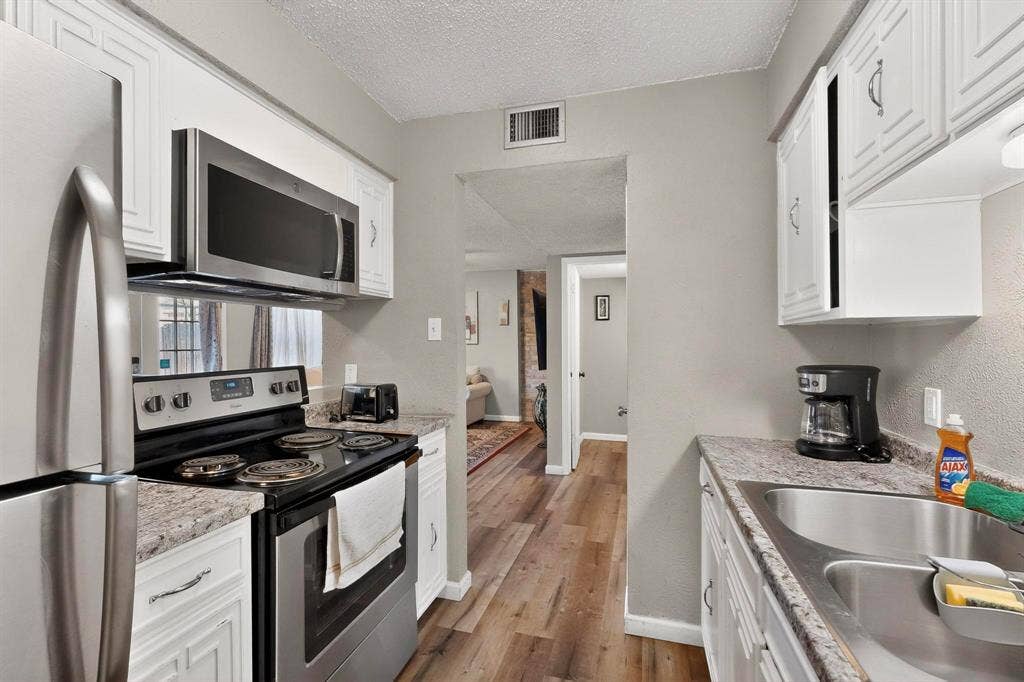 2315 Blue Sage Lane, Arlington, TX 76014 Kitchen featuring stainless steel appliances, white cabinets, a textured ceiling, and dark wood-style floors