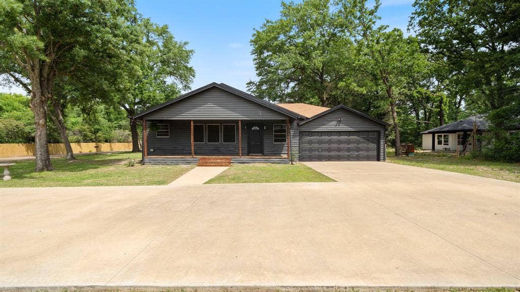 129 King Arthur Road, Mabank, TX 75156 Property exterior featuring dark gray siding, a covered porch with wooden posts, and an attached two-car garage