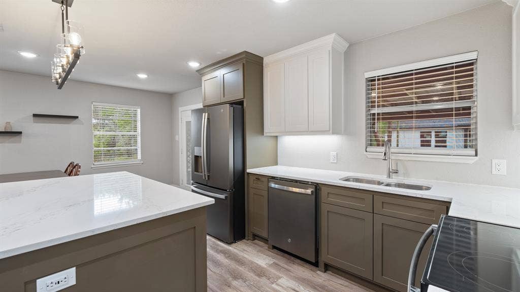 129 King Arthur Road, Mabank, TX 75156 The kitchen features an island with a light-colored countertop, stainless steel appliances, and a double basin sink