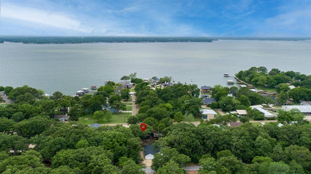 129 King Arthur Road, Mabank, TX 75156 Aerial view showcasing the property's location within a lush, tree-filled neighborhood, with a large body of water visible in the background and properties with private docks along the shoreline
