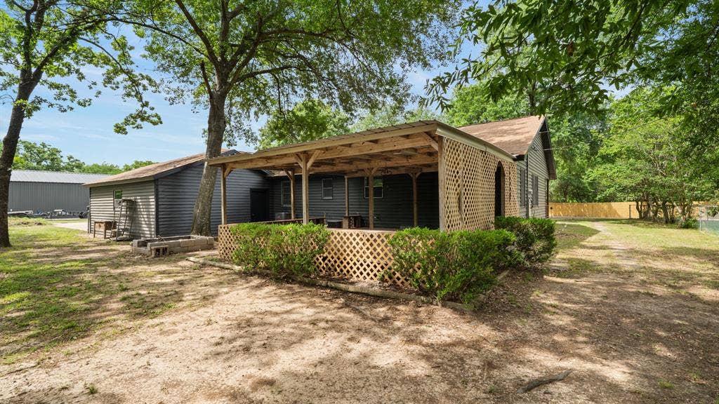 129 King Arthur Road, Mabank, TX 75156 The property features a covered porch with lattice screening, set against a backdrop of mature trees
