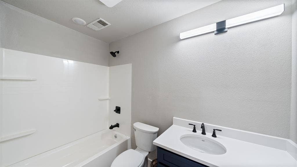 129 King Arthur Road, Mabank, TX 75156 The bathroom features a white bathtub with a shower, a vanity with a white countertop and sink, and a toilet