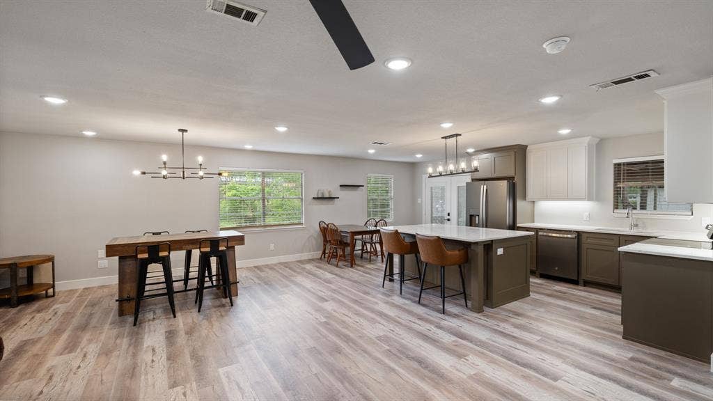 129 King Arthur Road, Mabank, TX 75156 The kitchen and dining area features recessed lighting, a large island with seating, stainless steel appliances, and wood-look flooring