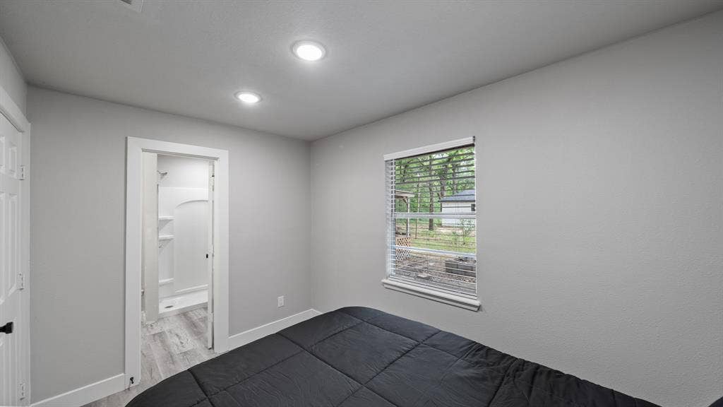 129 King Arthur Road, Mabank, TX 75156 Bedroom with recessed lighting, light gray walls, and a window with blinds overlooking greenery