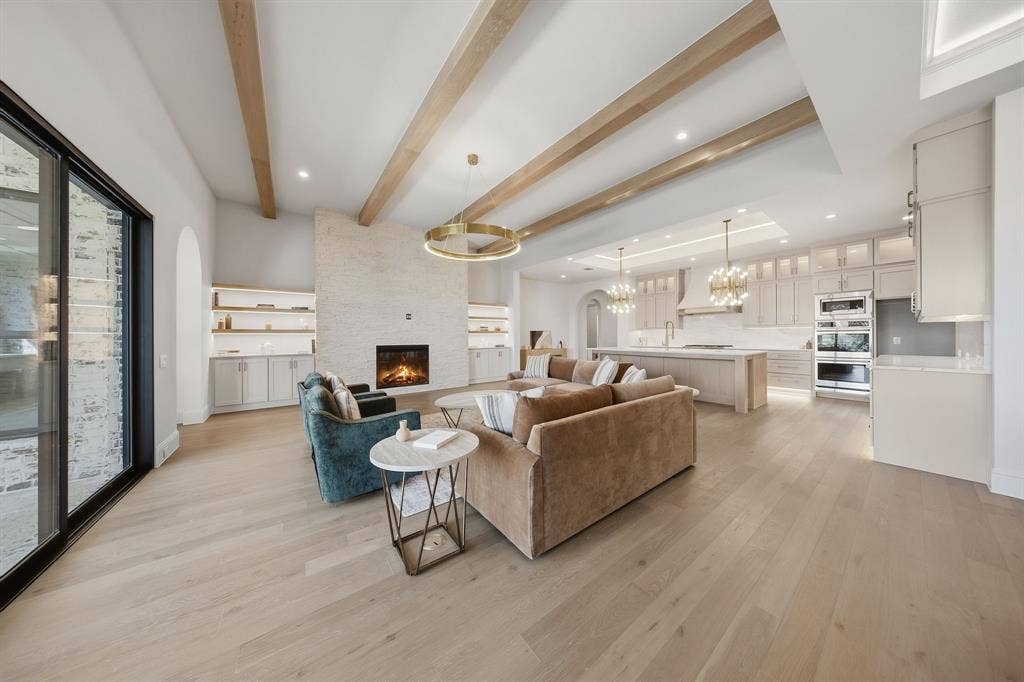 3333 Bridgegate Avenue, Northlake, TX 76247 Expansive living space featuring wood-finish flooring, a stone-clad fireplace, and exposed ceiling beams