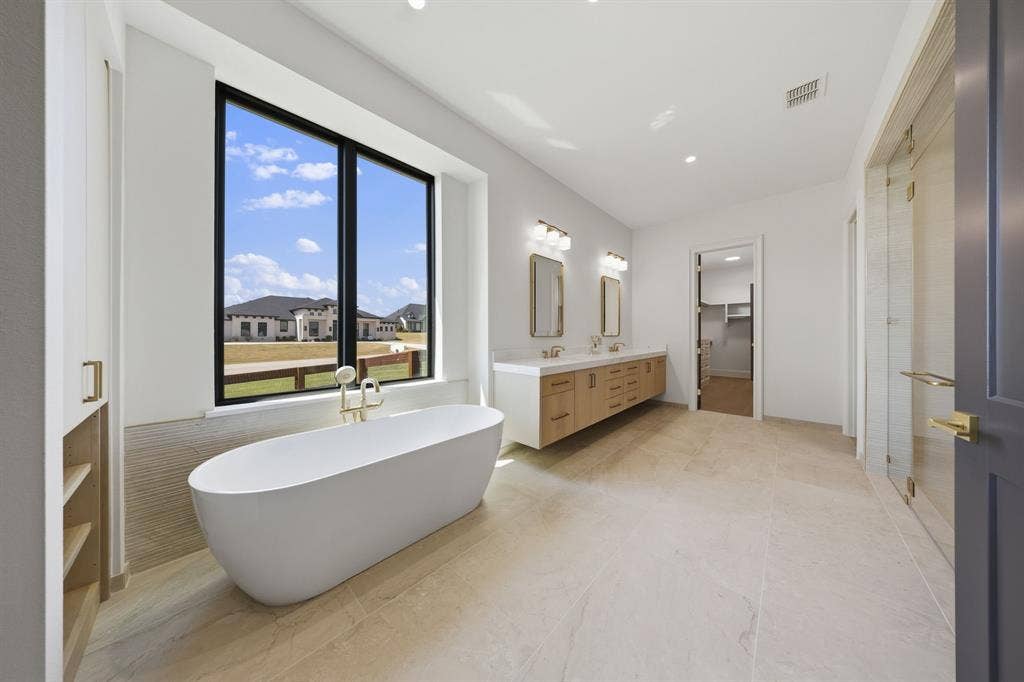 3333 Bridgegate Avenue, Northlake, TX 76247 Freestanding soaking tub with gold-finish fixtures, dual vanity with wood-finish cabinetry, and a large window with black trim