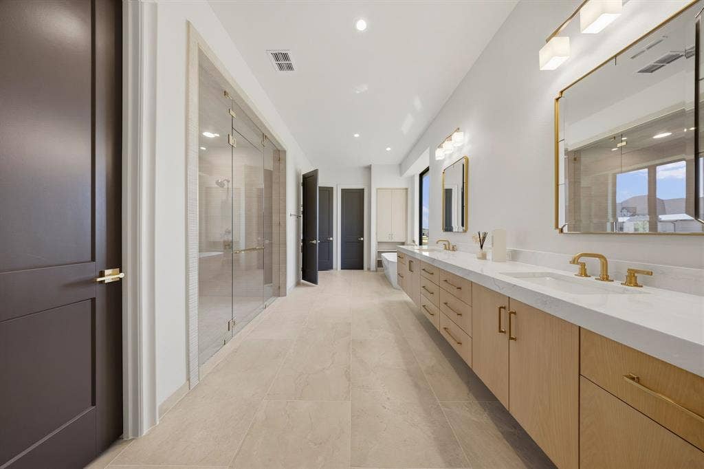 3333 Bridgegate Avenue, Northlake, TX 76247 Dual vanity with undermount sinks, light wood-finish cabinetry, gold-tone hardware and fixtures, and a glass-enclosed shower
