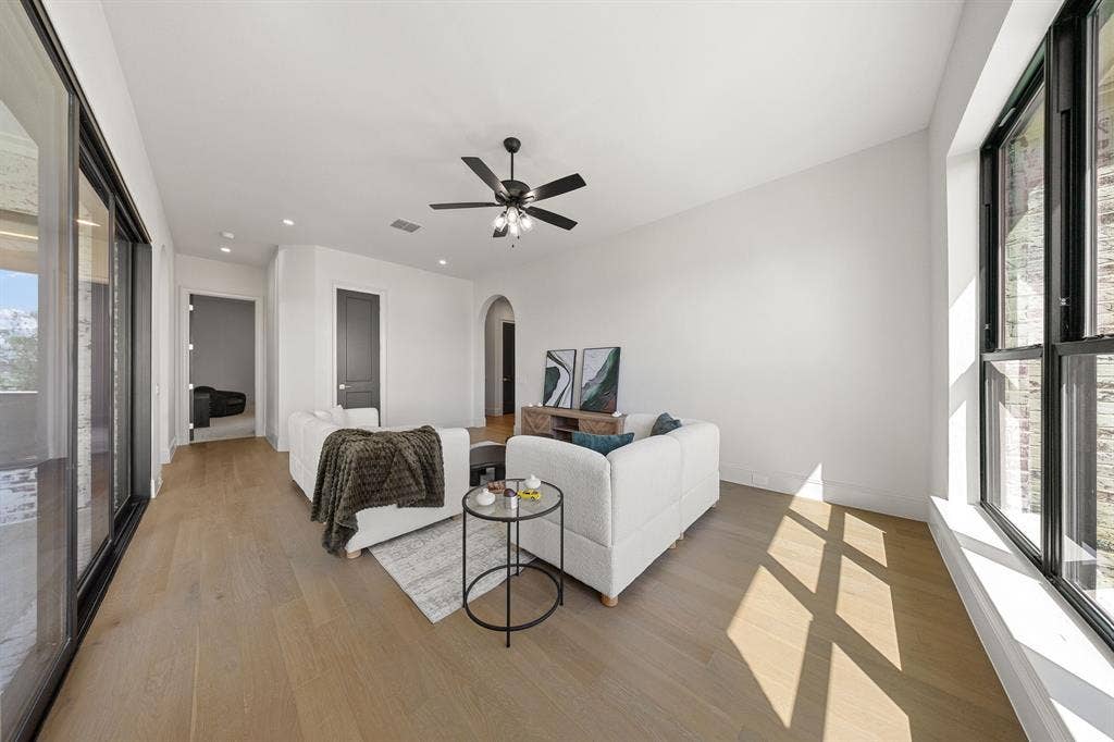 3333 Bridgegate Avenue, Northlake, TX 76247 Spacious living area featuring wood-finish flooring, a ceiling fan, large sliding glass doors, and tall windows
