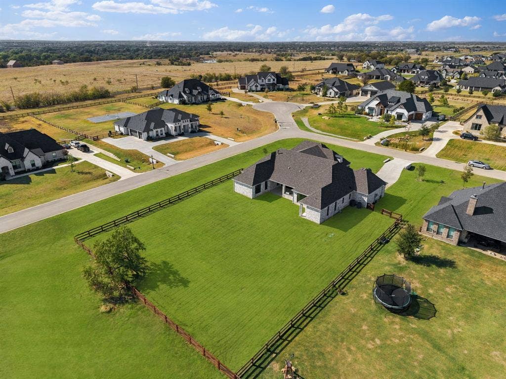 3333 Bridgegate Avenue, Northlake, TX 76247 Expansive grassy yard with perimeter fencing, mature tree, and a stone exterior residence featuring a multi-gabled roof