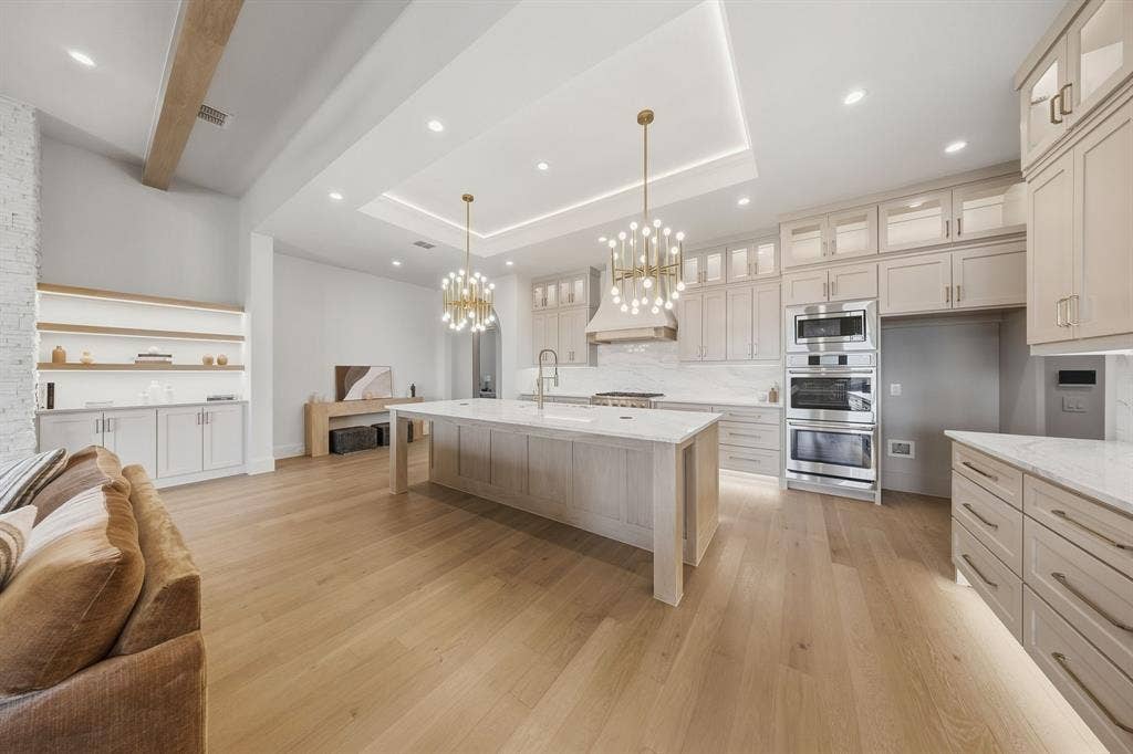 3333 Bridgegate Avenue, Northlake, TX 76247 Expansive kitchen featuring a large central island with countertop, extensive cabinetry, built-in double ovens, and wood-finish flooring