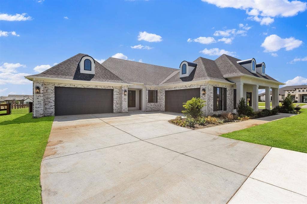 3333 Bridgegate Avenue, Northlake, TX 76247 Brick and stucco exterior, dark asphalt shingle roof, arched dormer windows, covered entry porch, and a concrete driveway