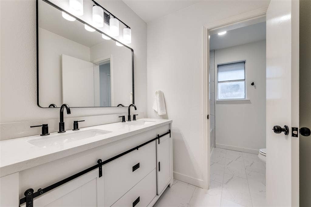 2601 Red Oak Lane, Plano, TX 75075 Updated guest bathroom with dual sink vanity, modern black fixtures, framed mirror, and upgraded lighting.