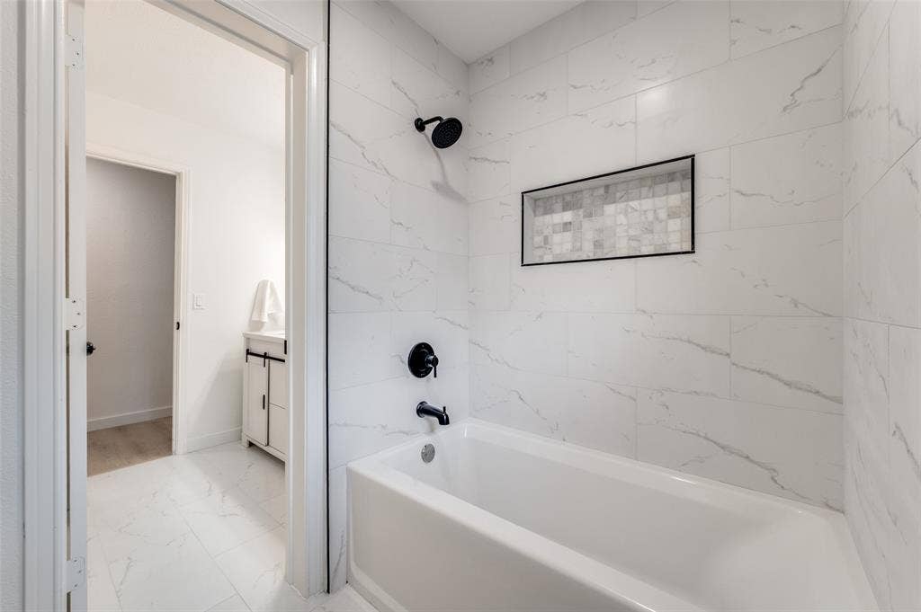 2601 Red Oak Lane, Plano, TX 75075 Tub / shower combo finished with porcelain tile, marble accent niche, and sleek black hardware.