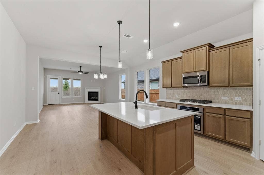 15056 Green Bluff Drive, Aledo, TX 76008 Spacious kitchen featuring a central island with quartz countertop, stainless steel appliances, and wood-finish cabinetry