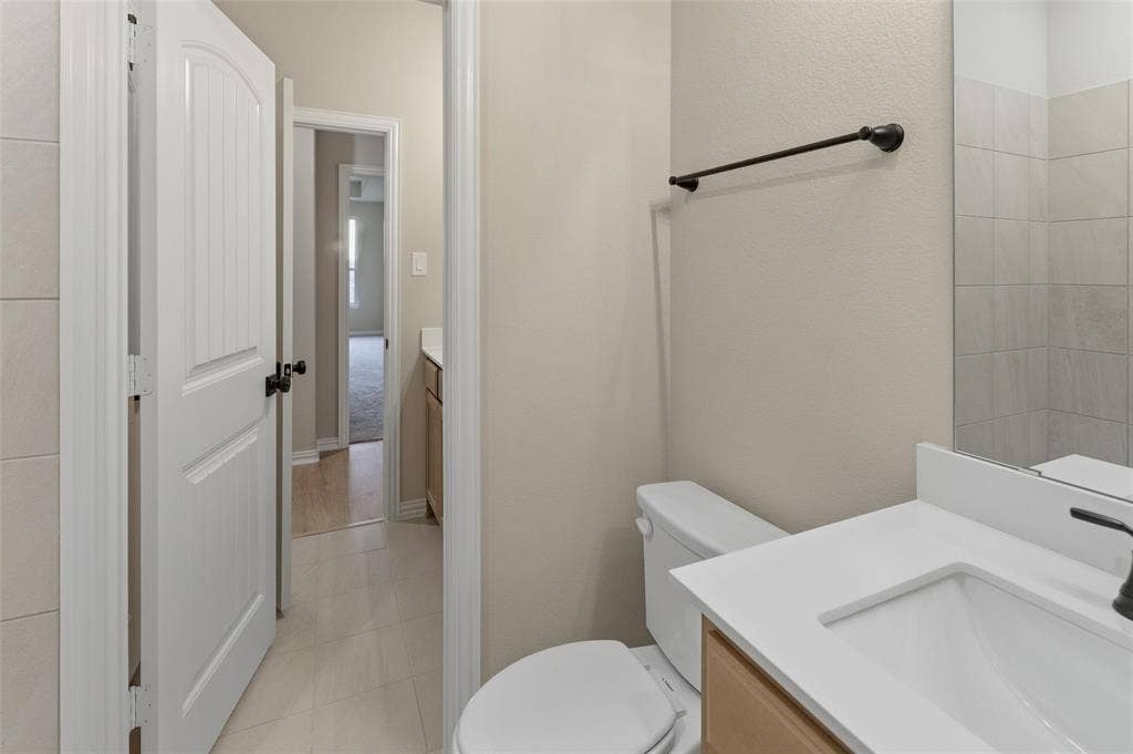 15056 Green Bluff Drive, Aledo, TX 76008 Bathroom featuring a single-sink vanity with a white countertop, under-mount sink, and dark-finish faucet