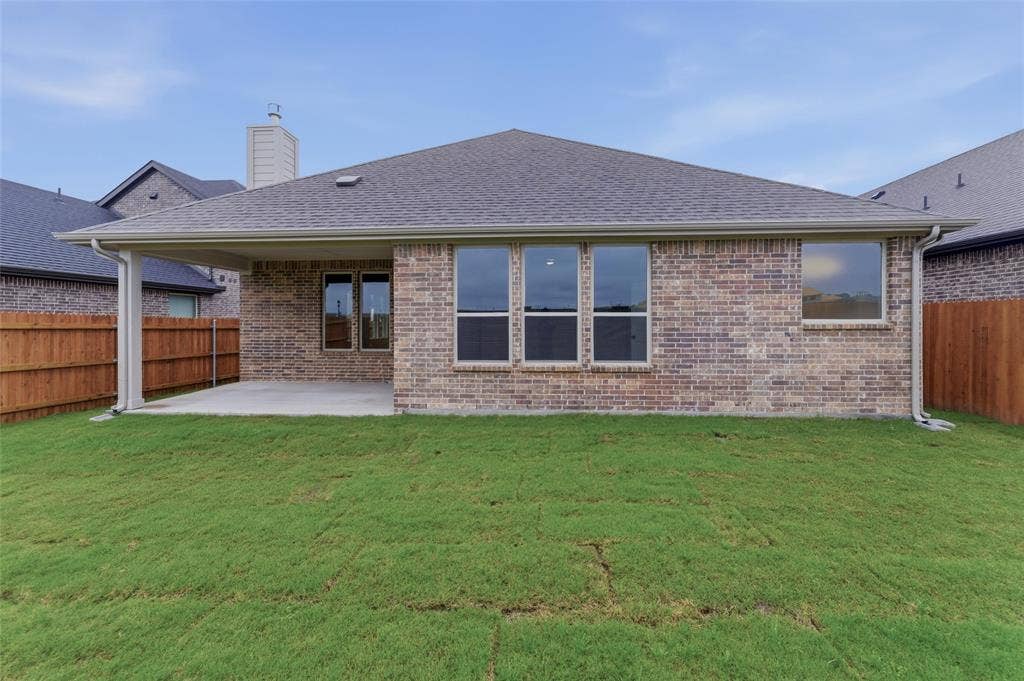 15056 Green Bluff Drive, Aledo, TX 76008 Rear exterior featuring a covered patio, brick facade, and a wood privacy fence