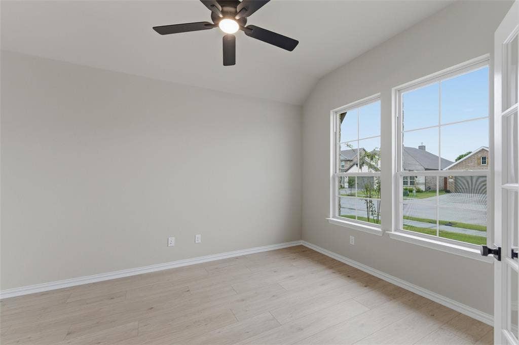 15056 Green Bluff Drive, Aledo, TX 76008 Vaulted ceiling room featuring light-toned wood-finish flooring, two large windows, a ceiling fan, and French doors with black hardware