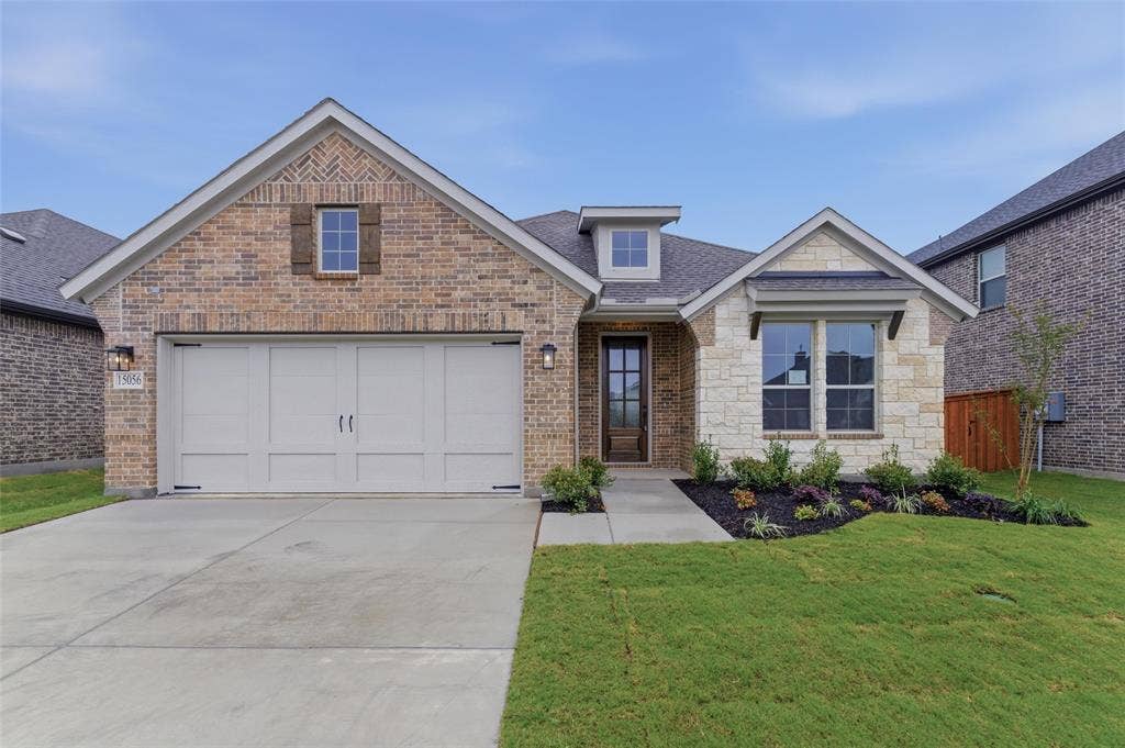 15056 Green Bluff Drive, Aledo, TX 76008 Charming facade featuring a two-car garage, brick and stone exterior, professional landscaping, and a welcoming entryway