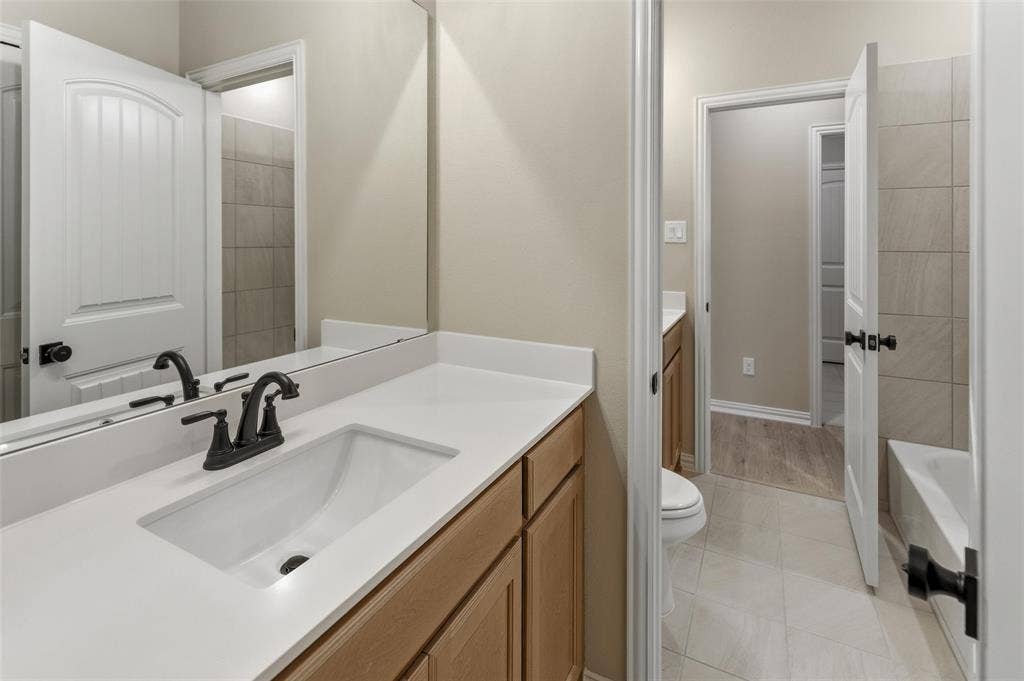 15056 Green Bluff Drive, Aledo, TX 76008 Bathroom vanity featuring an integrated rectangular sink, matte black faucet, and light wood-finish cabinetry