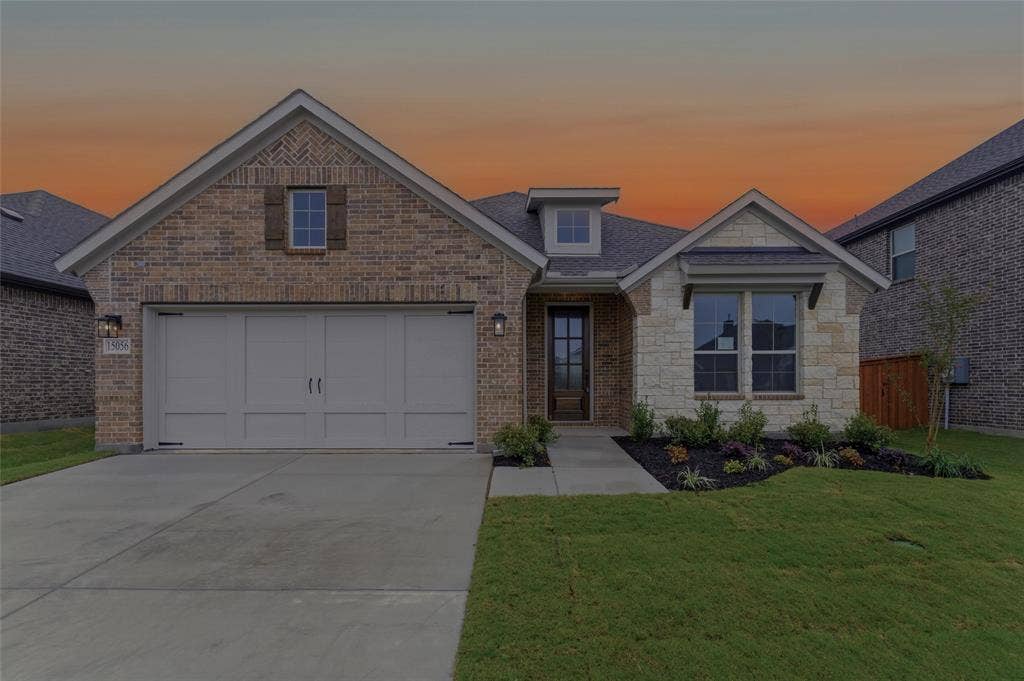 15056 Green Bluff Drive, Aledo, TX 76008 Brick and stone veneer exterior featuring a two-car garage with panel detailing