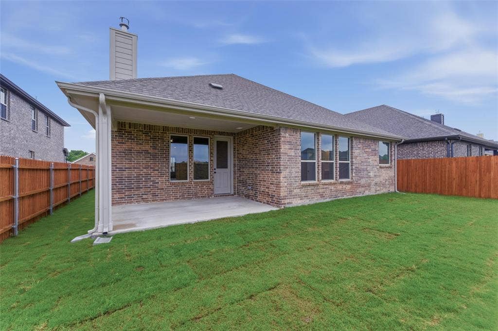 15056 Green Bluff Drive, Aledo, TX 76008 Expansive rear yard featuring a covered patio, brick exterior, multiple windows, and a privacy fence