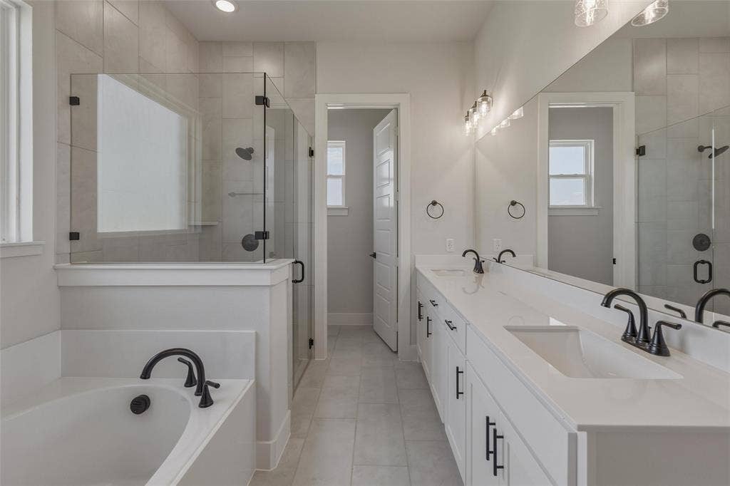 12117 Clastic Court, Krum, TX 76249 Modern bathroom featuring a dual vanity with white cabinetry and integrated sinks, a freestanding tub, and a frameless glass shower with matte black fixtures