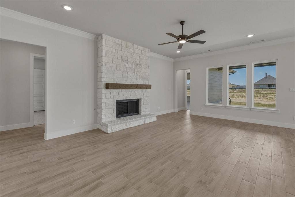 12117 Clastic Court, Krum, TX 76249 Living space featuring a stone fireplace with a wood-finish mantel, wood-finish flooring, recessed lighting, and multiple windows