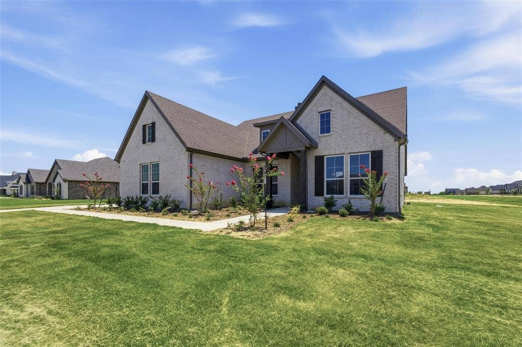 12117 Clastic Court, Krum, TX 76249 Brick exterior featuring dark window shutters, an entryway with a covered porch, and a dormer window