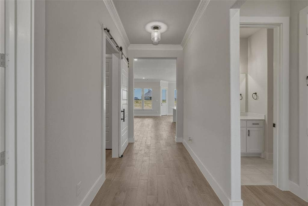 12117 Clastic Court, Krum, TX 76249 Hallway featuring wood-finish flooring, crown molding, and a visible barn door