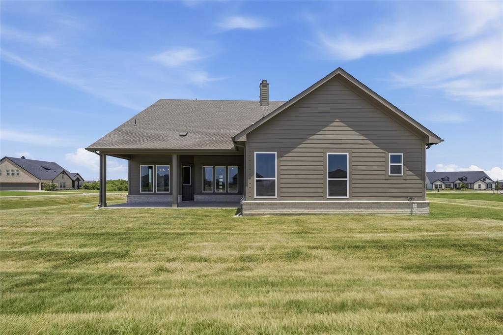 12117 Clastic Court, Krum, TX 76249 Rear exterior featuring a covered patio, multiple windows, siding facade, and a shingled roof