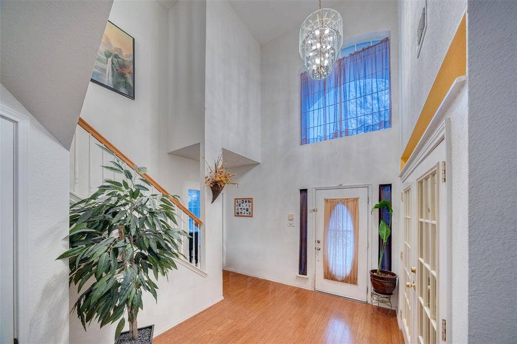 Entrance foyer featuring wood finished floors, a high ceiling, and hanging lights