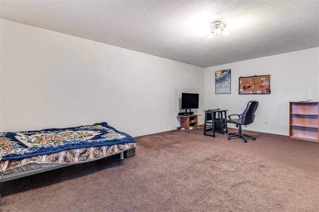 Bedroom featuring carpet floors, a textured ceiling, and a desk